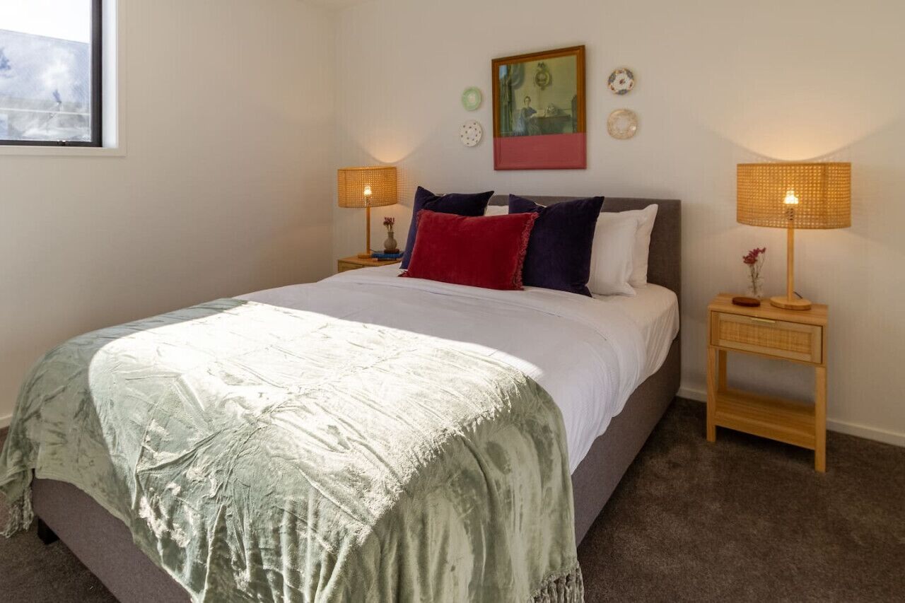 Une chambre à coucher avec un grand lit, deux tables de chevet et une fenêtre.