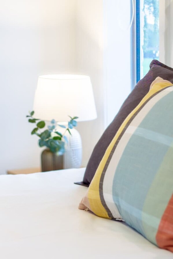 A neatly made bed with a pillow and a bedside lamp.