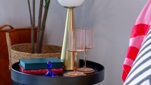 A round table with a lamp, books, and two glasses.