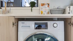 Una lavadora de carga frontal en una cocina compacta y moderna con una ventana arriba.