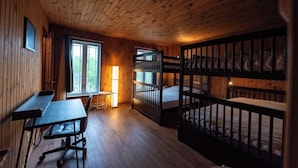 A cabin-style room with a wooden interior, a bunk bed, a desk, and a window providing a view of the outdoors. - Chalet in a dark sky reserve (Val-Racine)