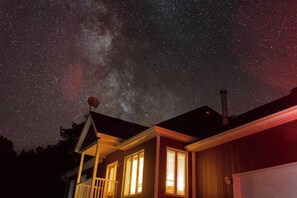 Una casa con cielo estrellado visible a través de la ventana, una antena parabólica en el techo y una chimenea.