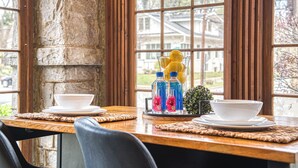 A dining table with two white bowls and two bottles of Fiji water, set against a stone wall with large windows. - Charming Vintage 1BR, 1BA Apartment in Midtown @Piedmont Park. (Atlanta)