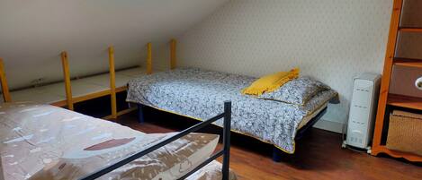 A dormitory room with bunk beds, a skylight, and a wooden dresser.