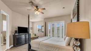 Un dormitorio con cama, ventilador de techo, cómoda, televisor y lámpara.