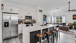 A modern kitchen with a central island, stainless steel appliances, and a dining area with bar stools. - WH485WP - Game Room | Private Pool | Newly Remodeled/Upgraded (Davenport)