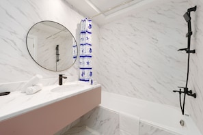 A bathroom with a marble wall, a round mirror, a white sink, a pink vanity, and a black shower. - Maison Privee - Superior Apt in Business Bay w/ Dubai Canal Views (Dubai)