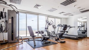 A spacious gym with cardio machines, weightlifting equipment, and large windows offering a view. - Maison Privee - Superior Apt in Business Bay w/ Dubai Canal Views (Dubai)