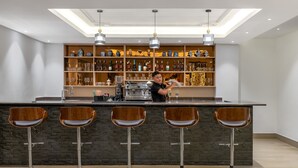 Ein stilvoller Barbereich mit Barkeeper, Barhocker und Regalen voller Spirituosenflaschen.