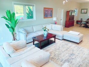 Un salon avec un canapé blanc, une table basse, une plante en pot et un tableau accroché au mur.