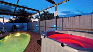 Un espace extérieur abrité avec une piscine, un jacuzzi et un escalier pour accéder à la piscine.
