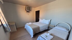 Una habitación de hotel con dos camas, un televisor instalado en la pared y un escritorio pequeño con una silla.
