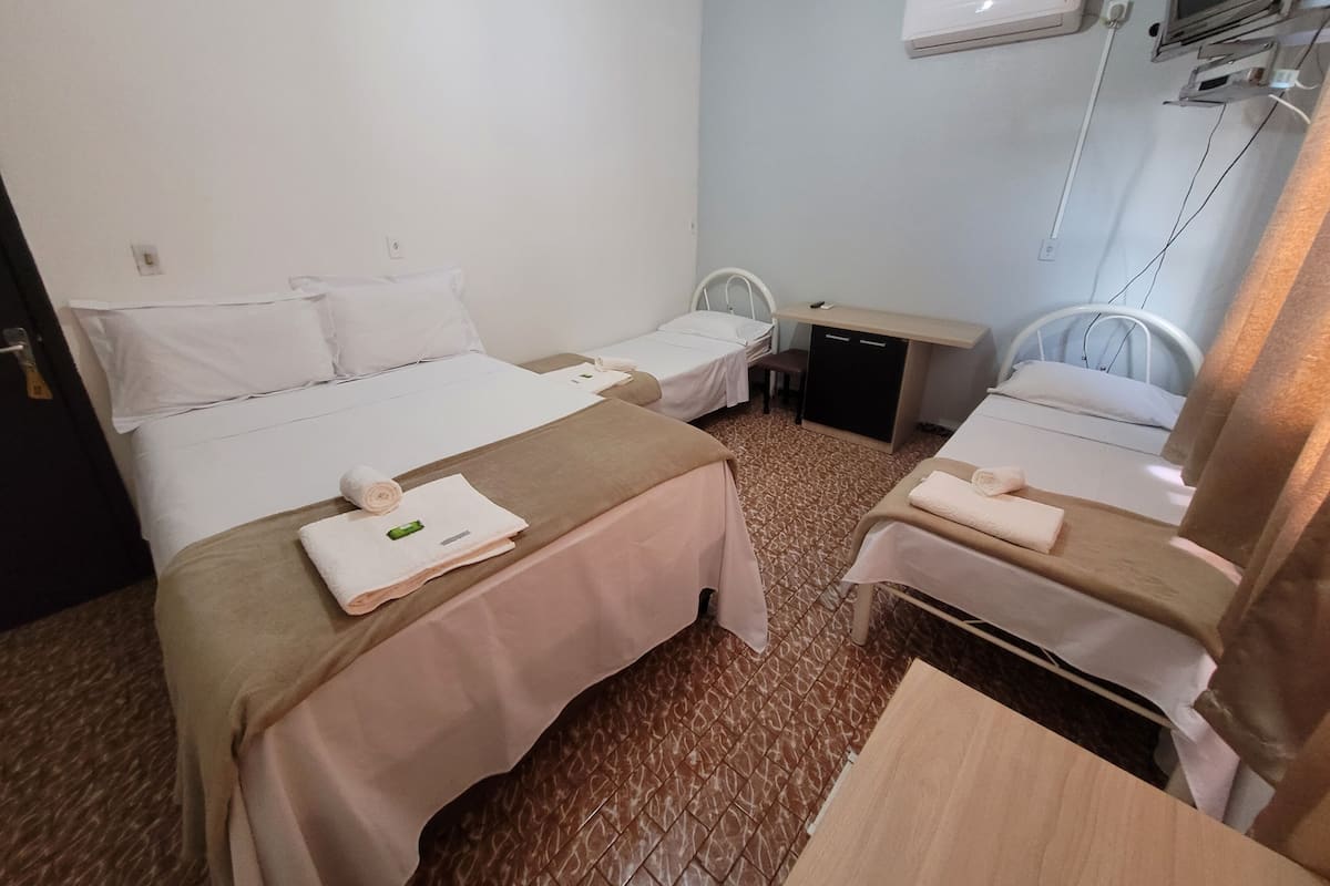 Habitación de hotel con dos camas, un escritorio, una silla, un aire acondicionado y un televisor.