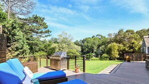 A deck with blue lounge chairs, a grill, and a view of a green landscape. - Beautiful waterfront home- mins to beach, fishing /kayak right from the backyard (Yarmouth)