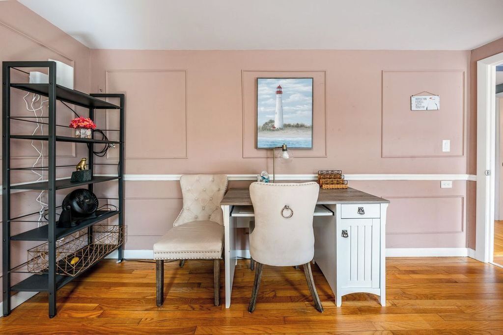 A room with a desk, two chairs, a bookshelf, and a framed picture of a lighthouse.