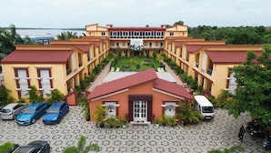 A multi-story hotel with a central courtyard, featuring a symmetrical design with a red roof and yellow walls.