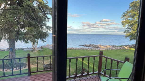 Une terrasse en bois offrant une vue sur un lac et une côte rocheuse.