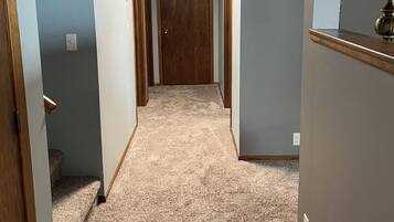 A hallway with carpeted floors, wooden doors, and light blue walls.
