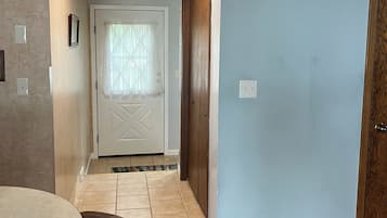 Un pasillo con una mesa de comedor y sillas, una puerta con diseño geométrico y suelo alfombrado.