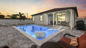 Ein Garten mit Swimmingpool, Gartenmöbeln und einer überdachten Terrasse.