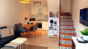 Un salon moderne comprenant un coin repas, une cuisine et un escalier orné de carreaux décoratifs.