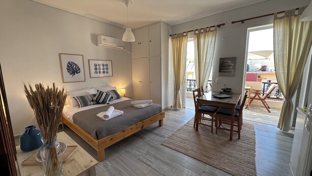 A bedroom with a bed, bedside table, and a view of the balcony. - Zen Studio 2 min from the beach with a spacious veranda, free WiFi, and A/C. (Rethymno)