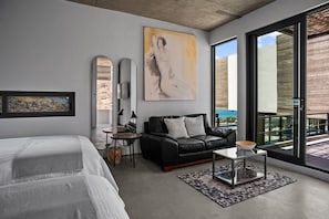 Ein modernes Schlafzimmer mit einem großen Bett, einer schwarzen Ledersofa, einem Glastisch und einem Gemälde an der Wand.