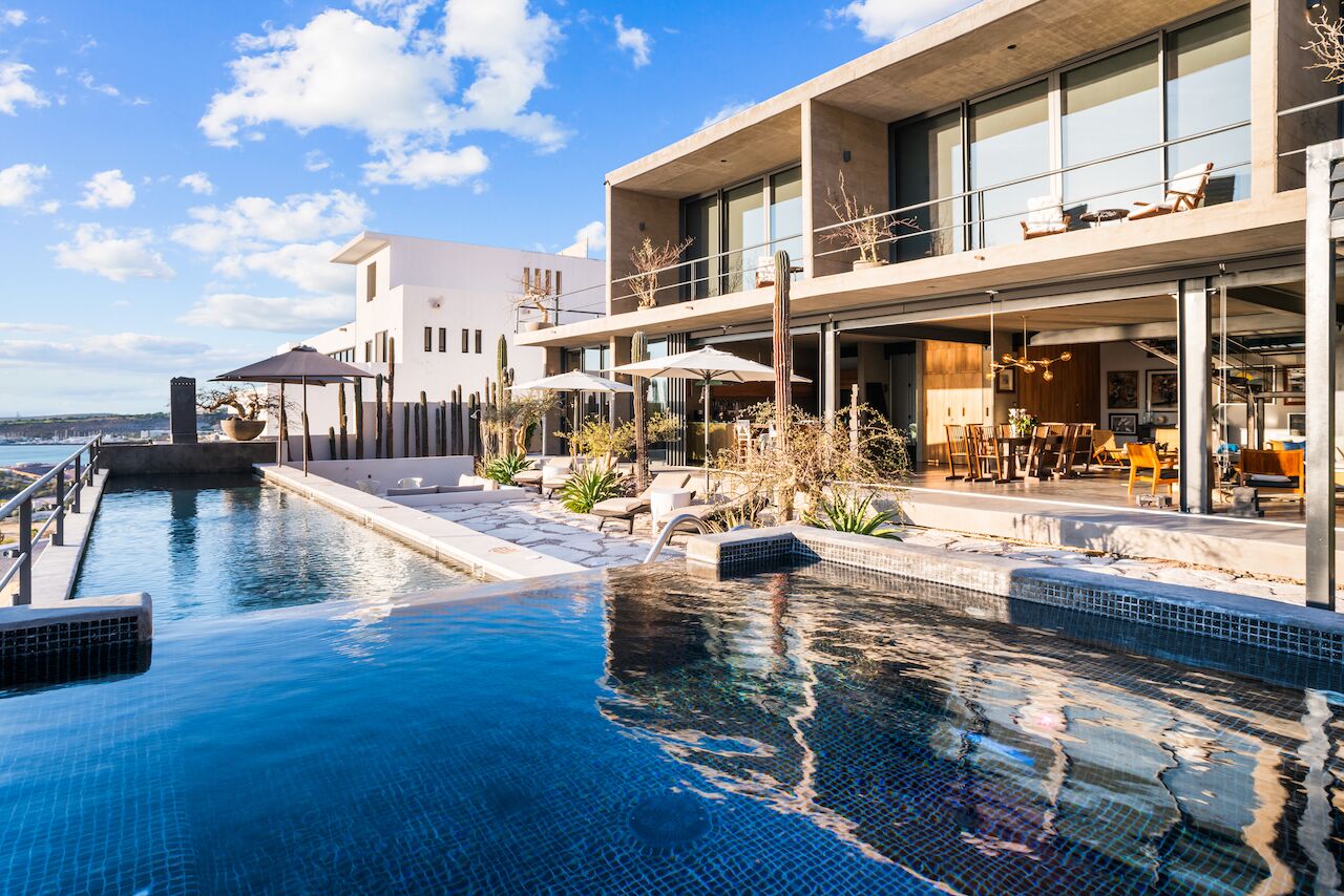 A modern hotel with a swimming pool, outdoor seating, and a view of the ocean.