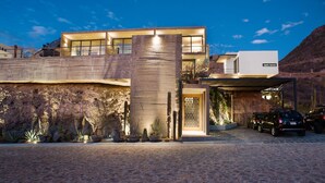 A modern house with a large patio area, a pool, and a desert landscape.