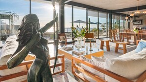 Un vaste espace de vie avec une grande fenêtre donnant sur un paysage magnifique, des meubles en bois et une statue.