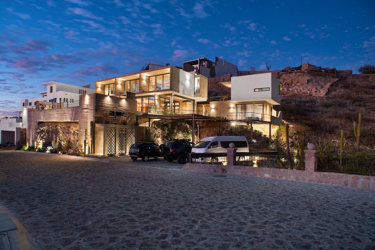 A modern multi-story house with a spacious driveway and parked vehicles.