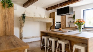 Une cuisine avec un îlot central en bois, des tabourets de bar, un four encastré et une grande fenêtre.