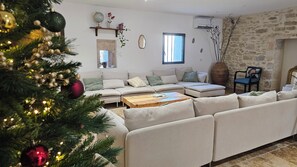 A living room with a sofa, a coffee table, a Christmas tree, and a stone wall. - Mas mes Aïeux (Saint-Rémy-de-Provence)