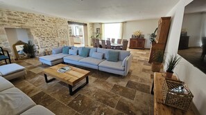 A living room with a sectional sofa, a wooden coffee table, and a stone wall. - Mas mes Aïeux (Saint-Rémy-de-Provence)