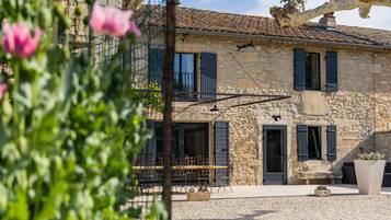 Un bâtiment en pierre avec un toit en tuiles, un balcon et une porte avec des volets.