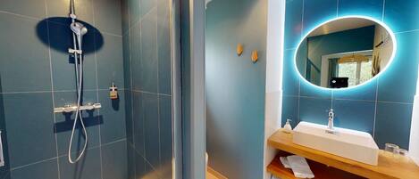 Une salle de bain moderne équipée d’une douche, d’un lavabo et d’un miroir.