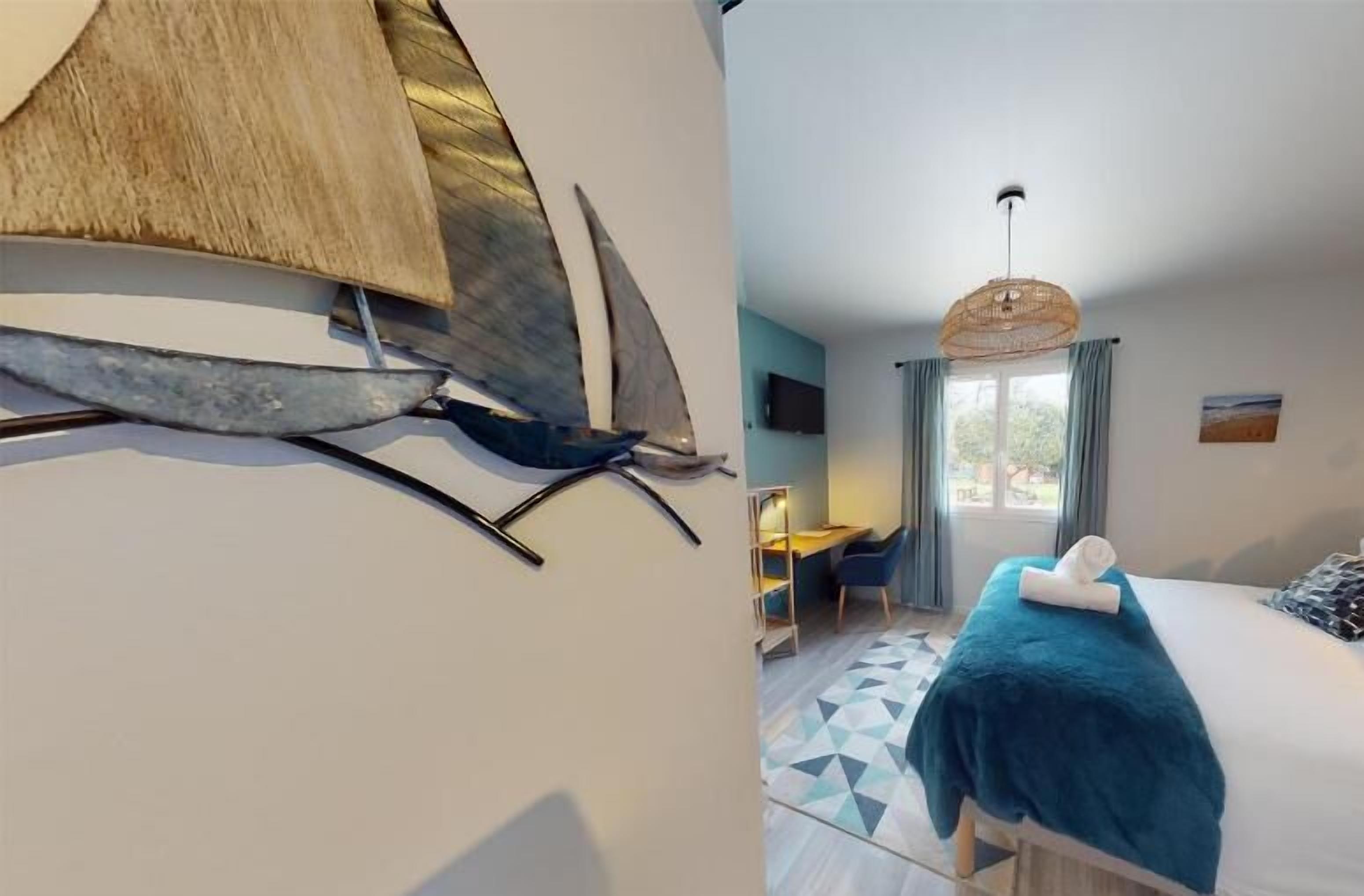 A modern hotel room with a bed, a desk, and a large window.