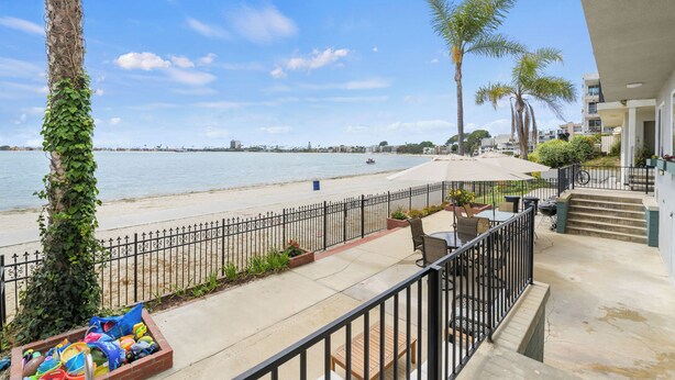 A balcony with a view of the beach, a palm tree, and a clear sky. - Condo on the Bay! Prime Location!  (San Diego)