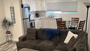 A modern living room with a sectional sofa, a coffee table, and a dining area with chairs and a table. - Condo on the Bay! Prime Location!  (San Diego)