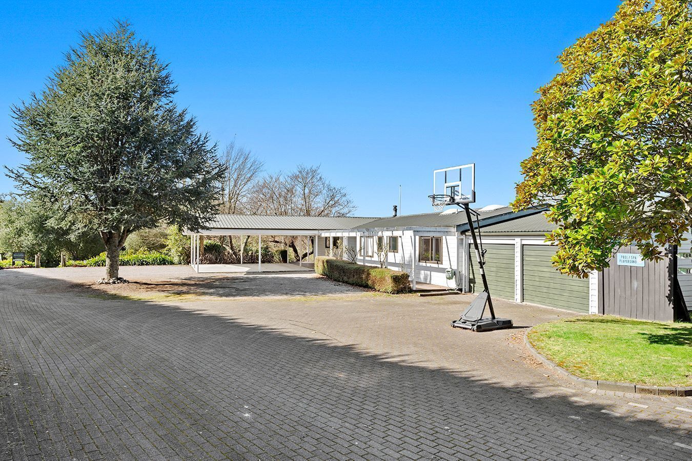 A residential area with a covered patio, a basketball hoop, and a house with a garage.
