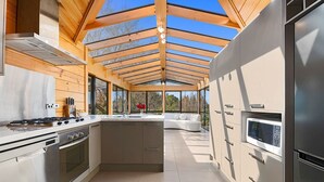 Une cuisine moderne dotée d’un îlot central, d’appareils électroménagers en acier inoxydable et d’un plafond en verre.
