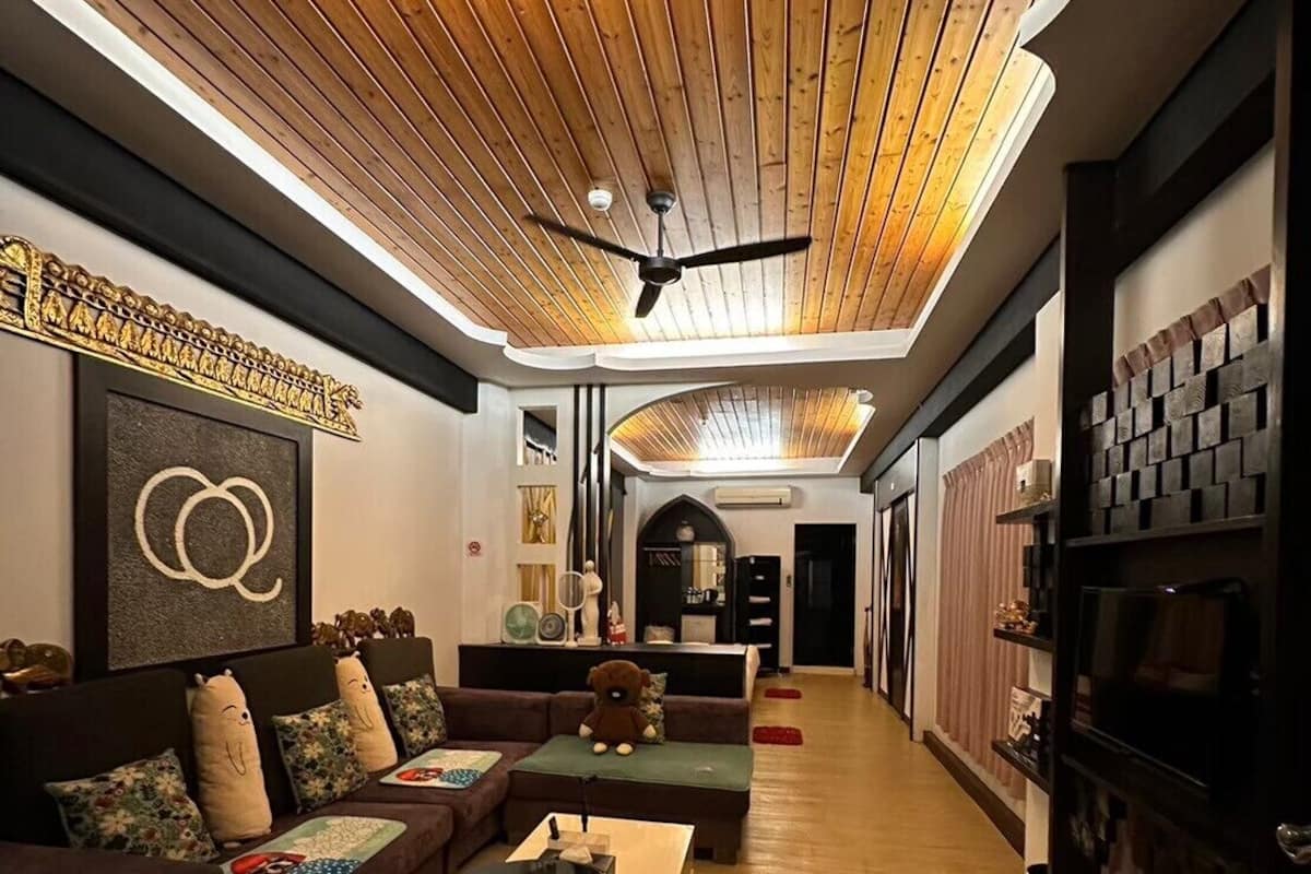 A modern living room with a wooden ceiling, a sofa set, a coffee table, and a TV.