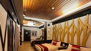 A hotel room with a wooden ceiling, a large bed with red and white bedding, a desk, and a mirror.