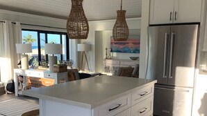 Uma cozinha moderna com uma ilha grande, armários brancos e eletrodomésticos de aço inoxidável.