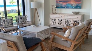 Uma sala de estar moderna com vista para o oceano, um armário branco com objetos decorativos e um quadro na parede.