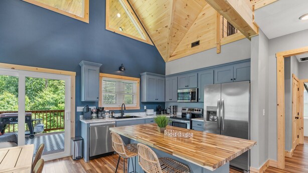 Una cocina moderna con una isla grande, techo de madera y armarios azules.