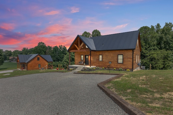 A log cabin with a gravel driveway and a small porch.