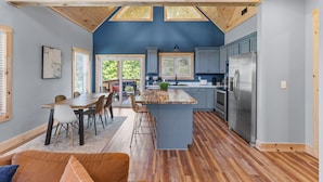 Una cocina moderna con una isla central, vigas de madera y vistas al exterior.