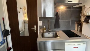 A compact kitchen with a built-in oven, microwave, and dishwasher. - Cosy Studio Saint Lazare (Paris)