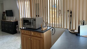 A modern kitchen with a built-in microwave, wooden cabinets, and a large window with a view of the outdoors. - Studio Cosy (Mende)